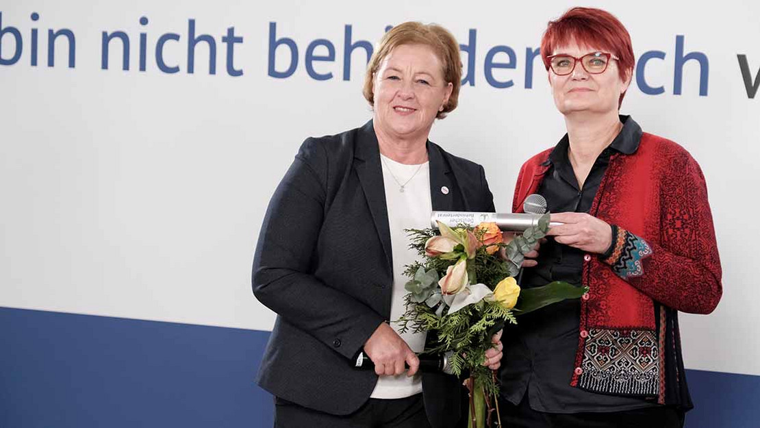 Zwei Frauen auf dem Podium mit Blumenstrauß und Staffelstab