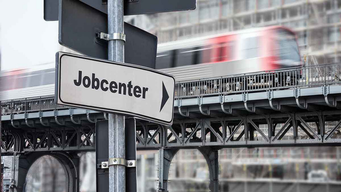 Wegweiser "Jobcenter" in einer Stadt. 