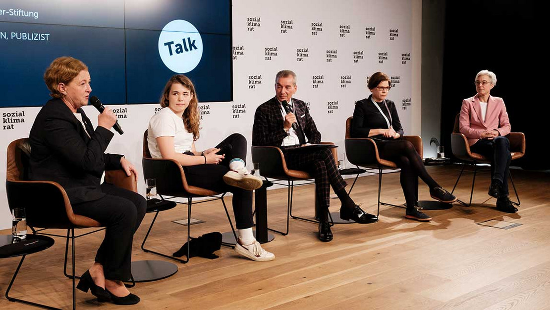 Fünf Personen bei einer Podiumsdiskussion auf einer Bühne. 